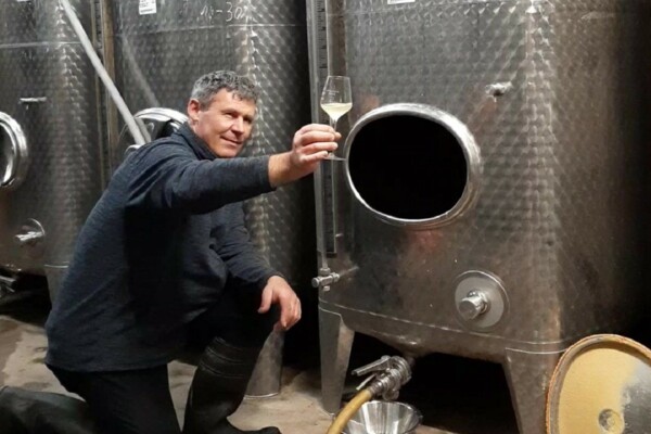 Winzer im Weinkeller vor dem Edelstahltank mit einem Weinglas in der Hand ©Weingut August Perll Winzer im Weinkeller vor dem Edelstahltank mit einem Weinglas in der Hand ©Weingut August Perll