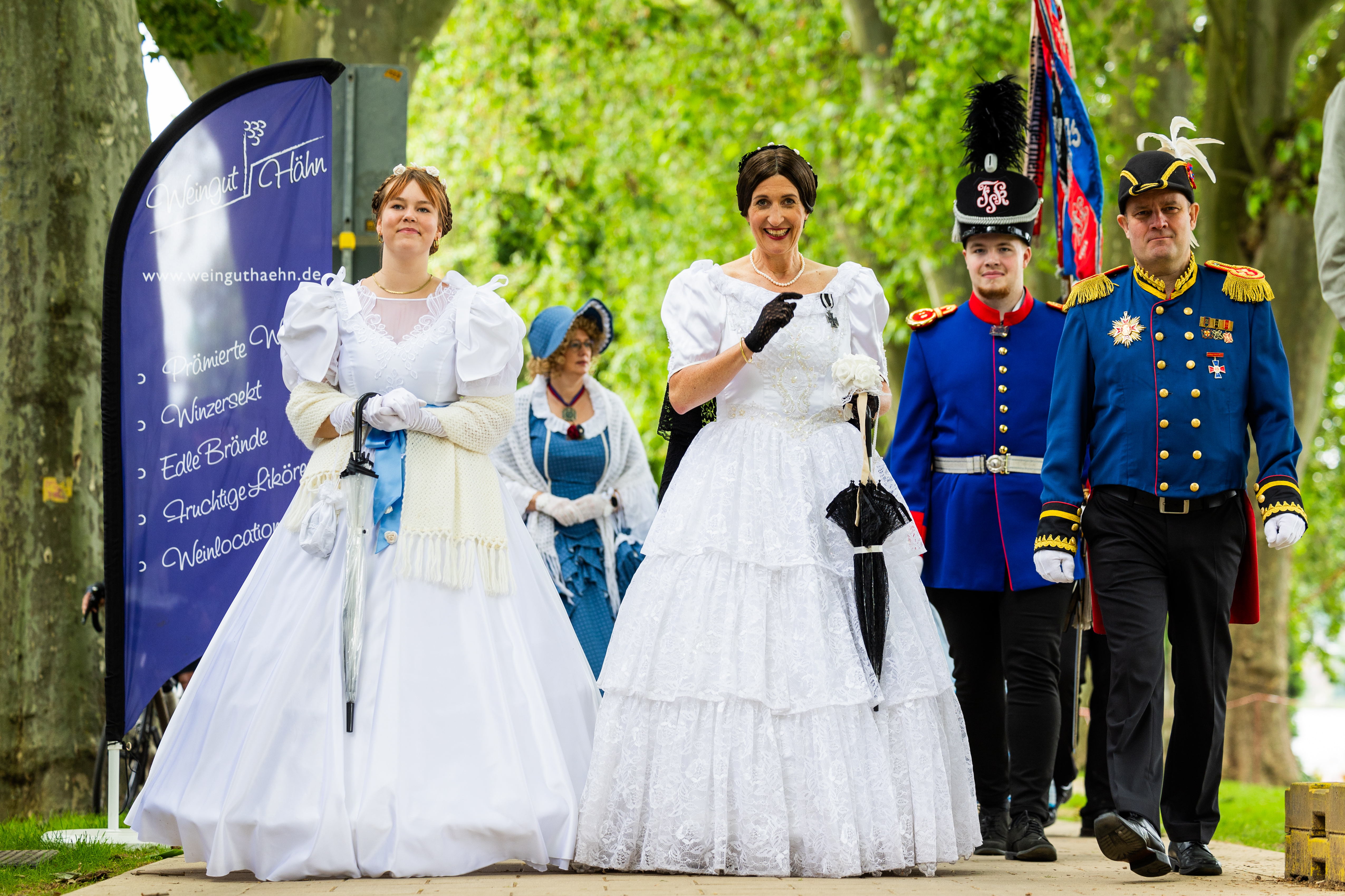 Kaiserin August l&auml;chelt mit Ihrem tollem Kleid in die Kamera. Drumherum und hinter Ihr sind weitere Personen mit Uniform und Kleidern.  &copy; Koblenz-Touristik, Kai M&uuml;ller