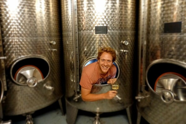 Winzer im Weinkeller schaut aus der Öffnung des Edelstahltanks mit einem Glas Wein in der Hand ©Weingut Gansen